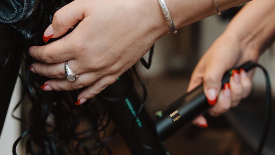 Stylist curling hair at Naomi Cuts Curls, Kelowna, British Columbia, CA with precision and care.