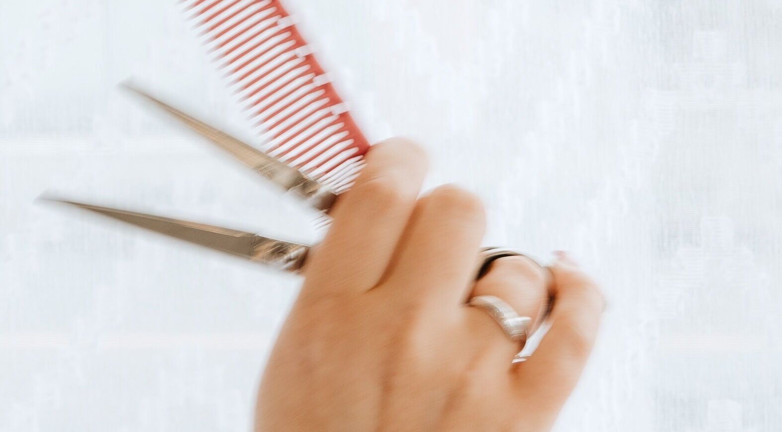 Hand holding scissors and comb at Naomi Cuts Curls, Kelowna, British Columbia, CA.