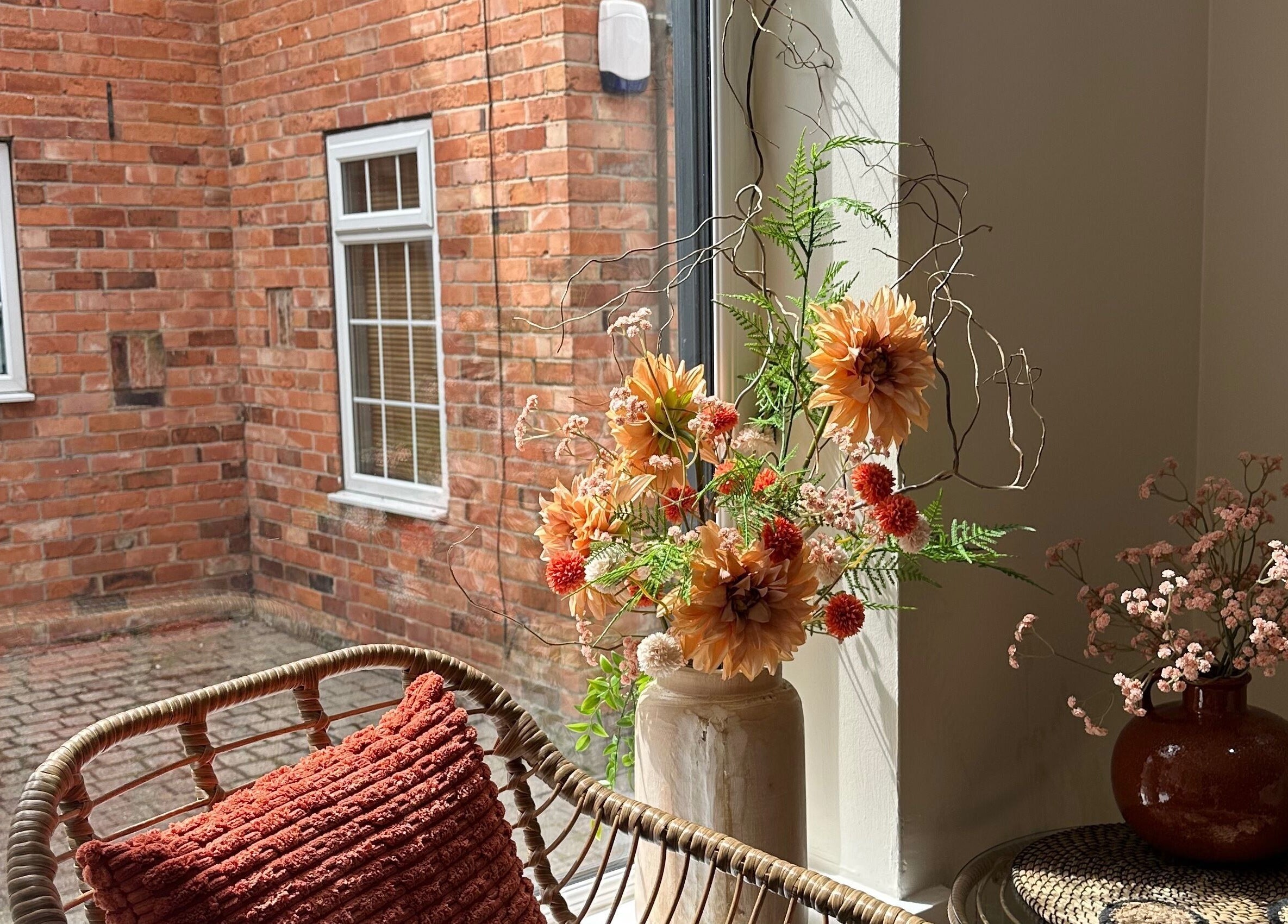 Cozy seating with florals by window at Faith & Co., Epworth, England, GB showcasing rustic brick beauty.