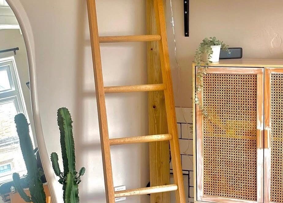 Interior of Jadene Tattoos, Leeds, England, with wooden ladder, plants, and woven cabinet.