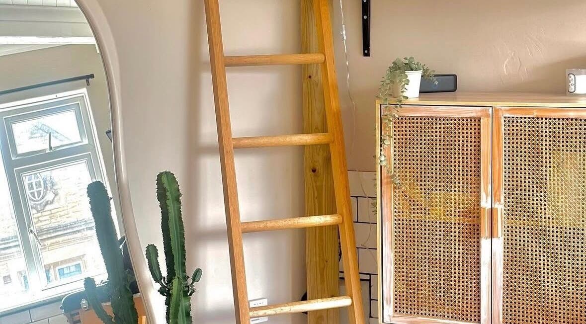 Interior of Jadene Tattoos, Leeds, England, with wooden ladder, plants, and woven cabinet.