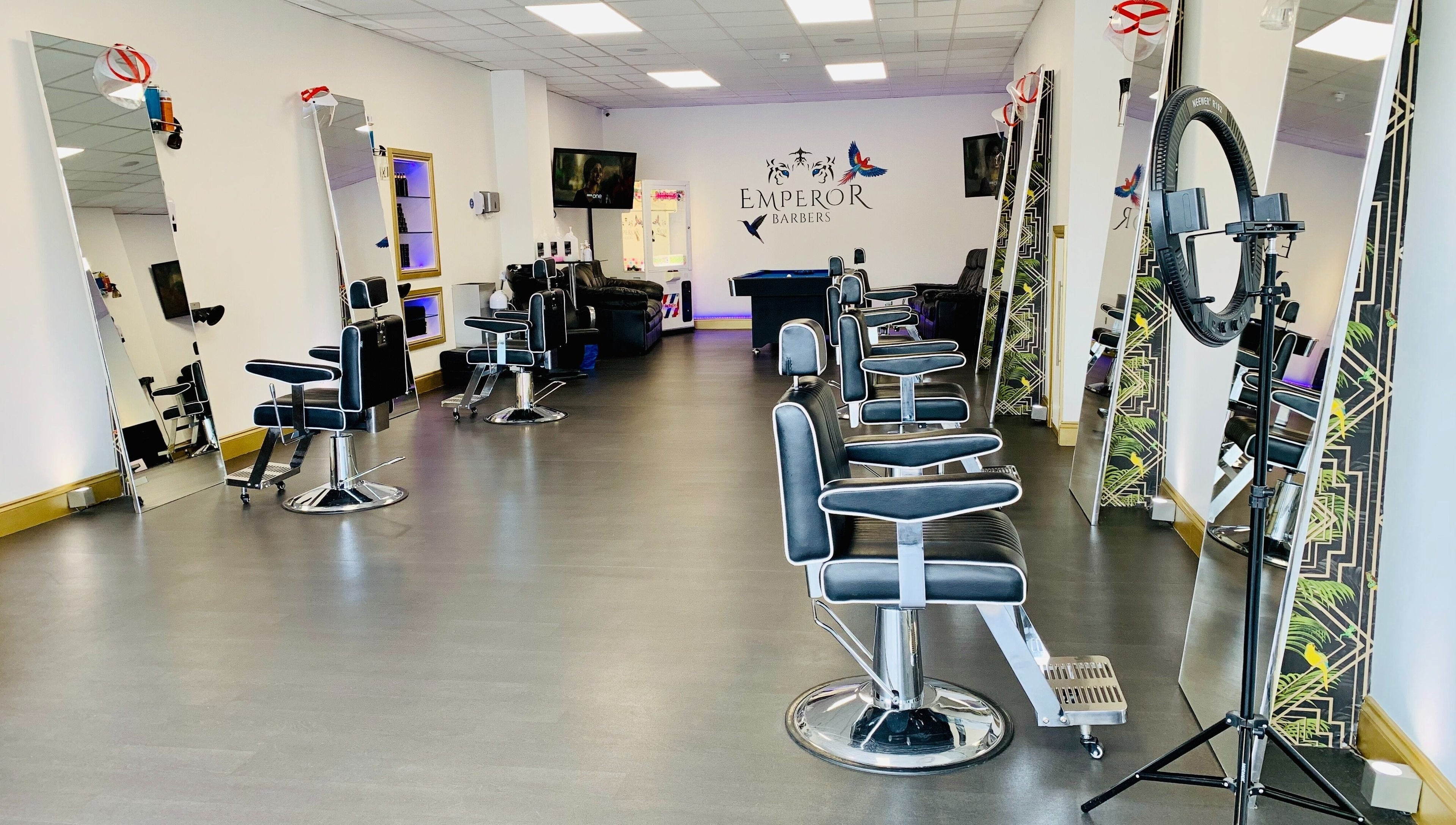 Modern interior of Emperor Barbers in Dunstable, England, GB, featuring stylish barber chairs and mirrors.