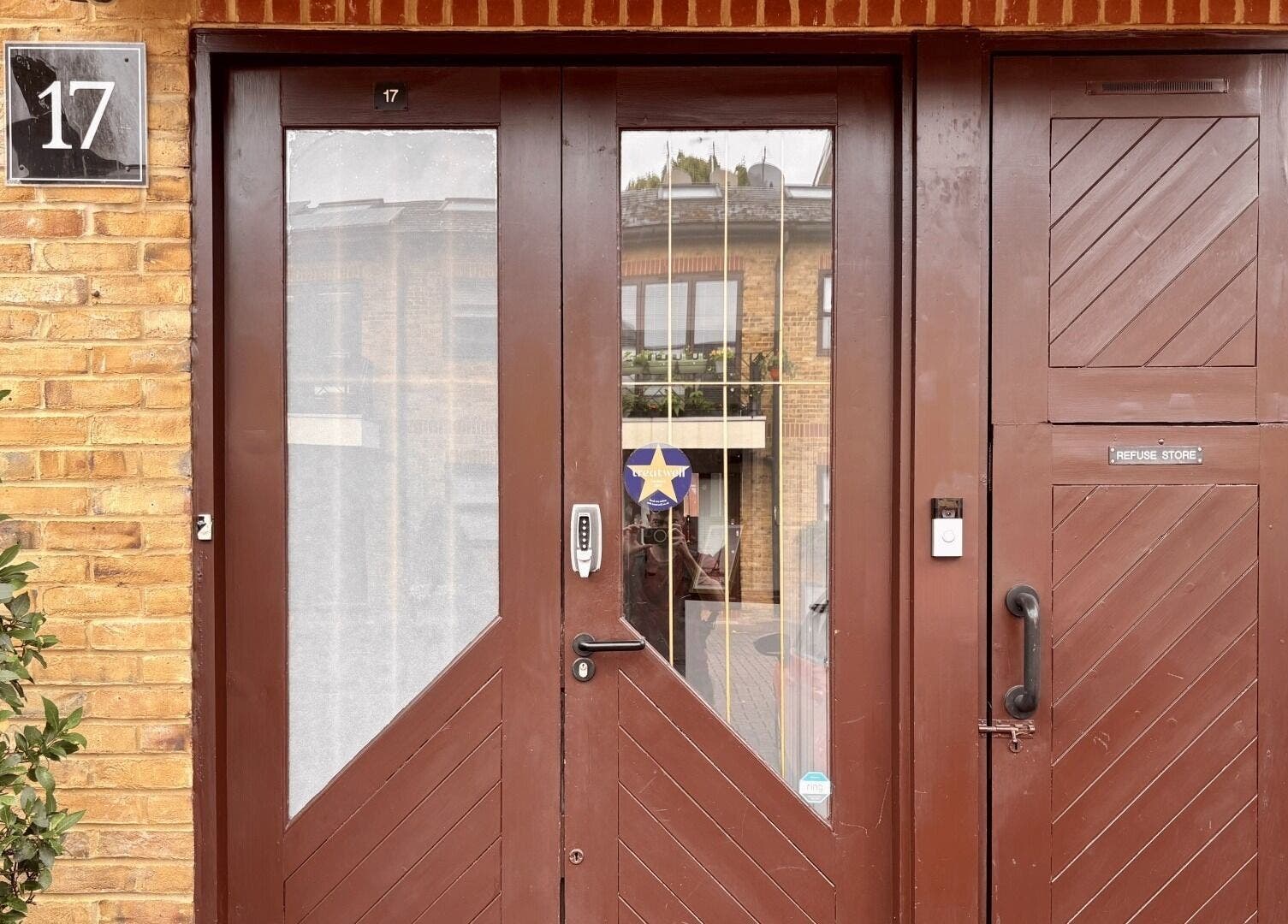 Main entrance of Osteotherapy Lab in London, England, GB, featuring wooden doors and a potted plant.