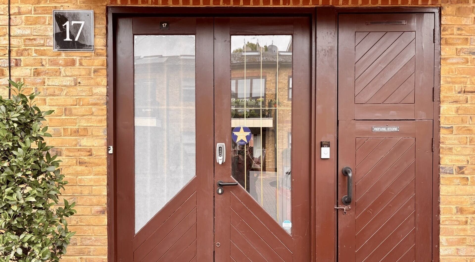 Main entrance of Osteotherapy Lab in London, England, GB, featuring wooden doors and a potted plant.