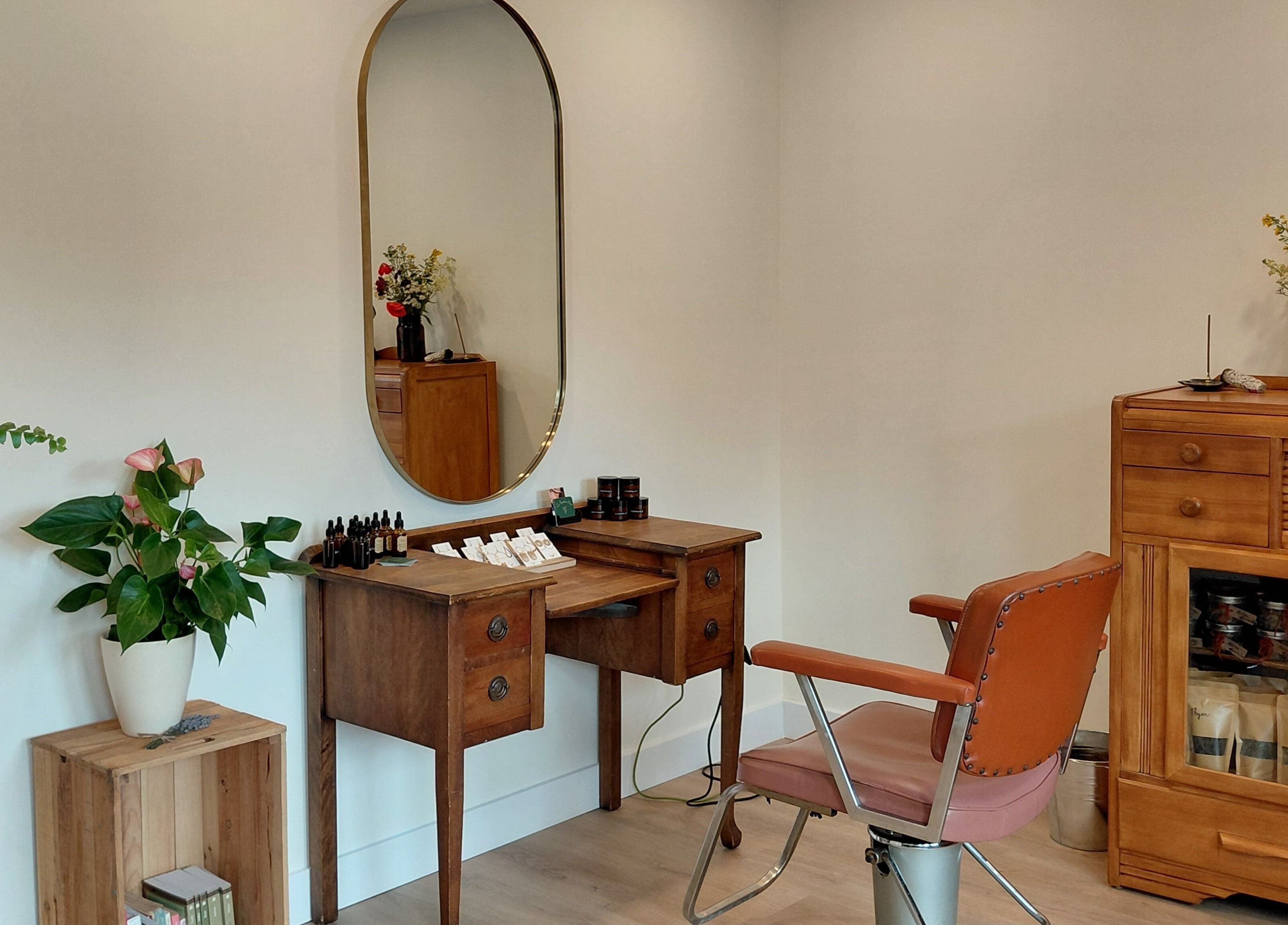 Coin salon vintage chez L'Apothic'Hair à Val-david, Québec, CA avec meuble bois et miroir orné.