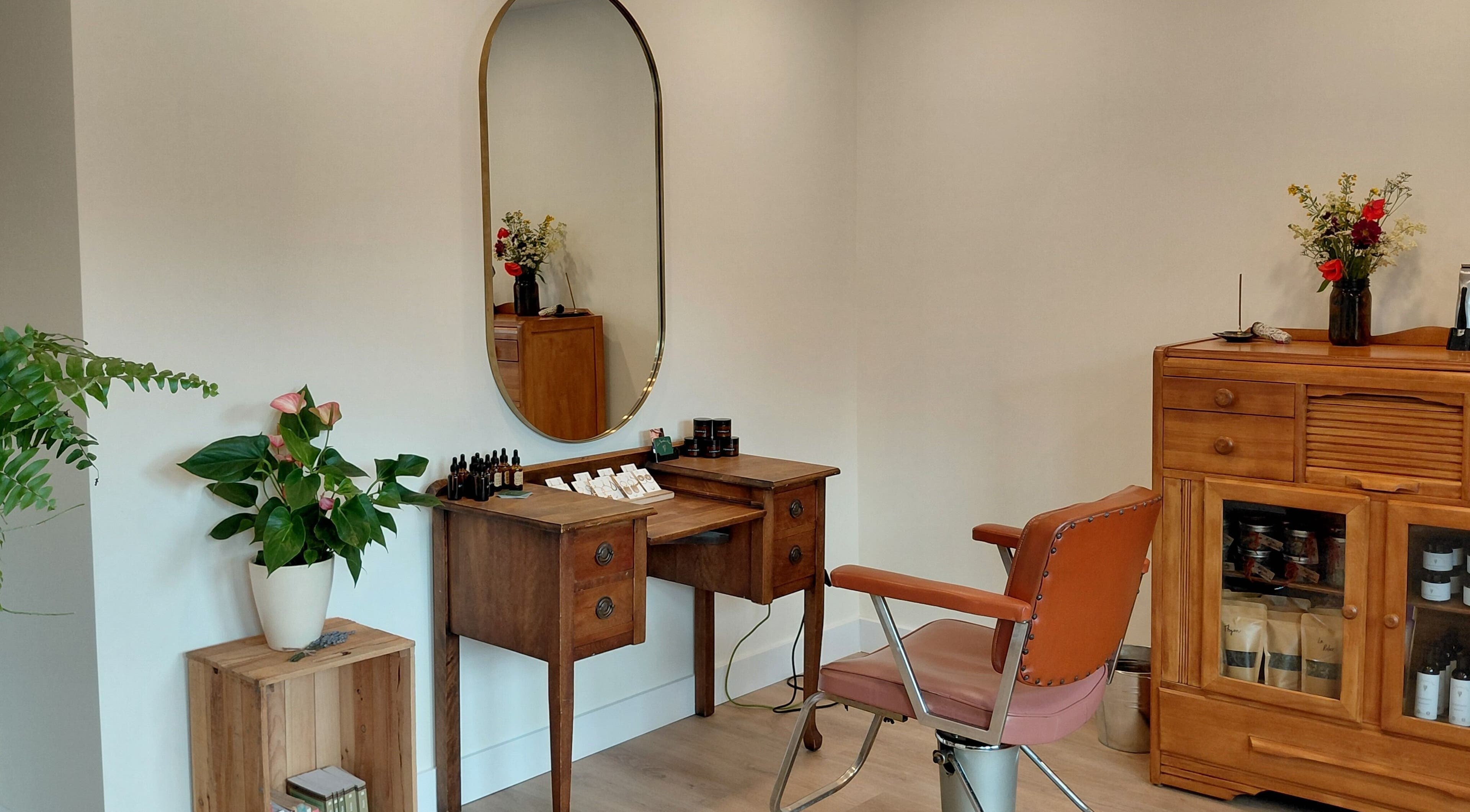 Coin salon vintage chez L'Apothic'Hair à Val-david, Québec, CA avec meuble bois et miroir orné.