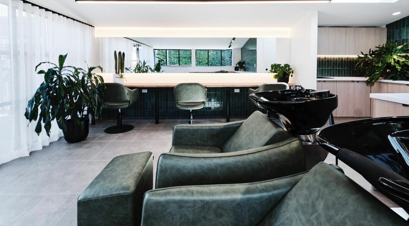 Modern interior at Maddy Hall Hair, Melbourne, Victoria, AU, featuring sleek chairs and green decor.