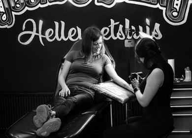 Vrouw krijgt tatoeage bij Goons & Queens Hellevoetsluis, Zuid-Holland, NL in ontspannen sfeer.