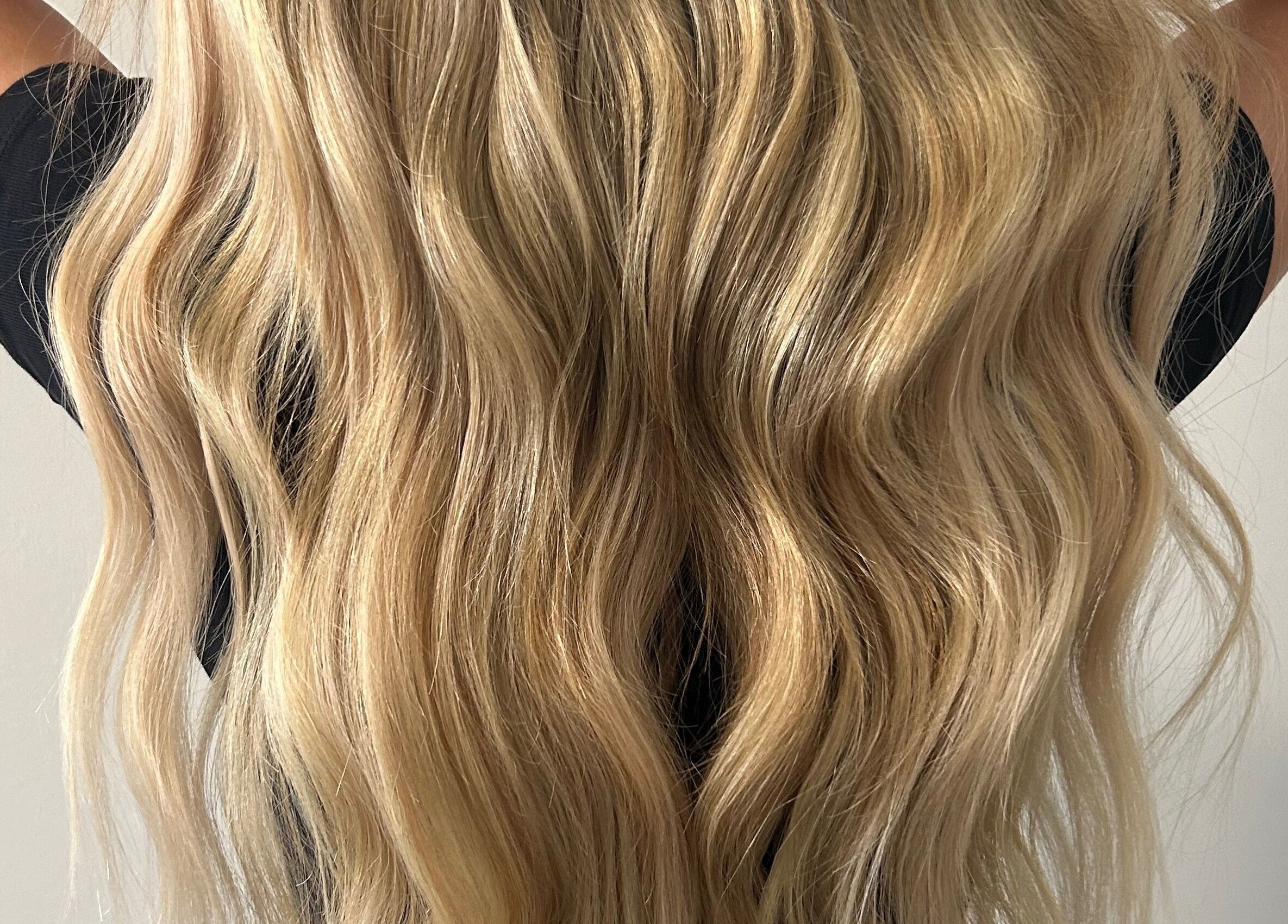 Blonde hair extensions styled at Katie Brady Hair Extensions in Smiths Falls, Ontario, CA, showcasing vibrant waves.