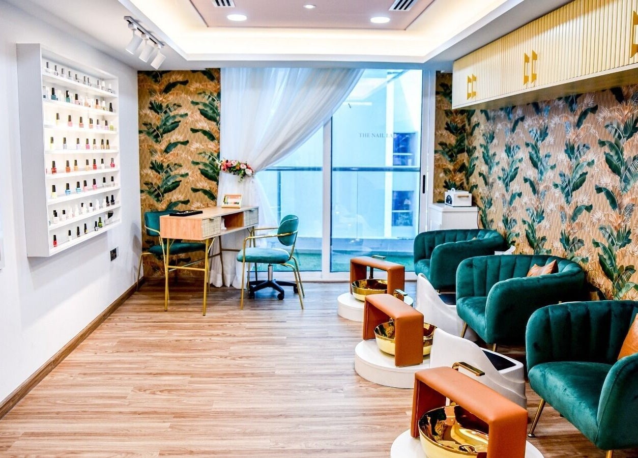Chic interior at The Beauty Lab Ladies Salon in Abu Dhabi, AE with green chairs and tropical wallpaper.