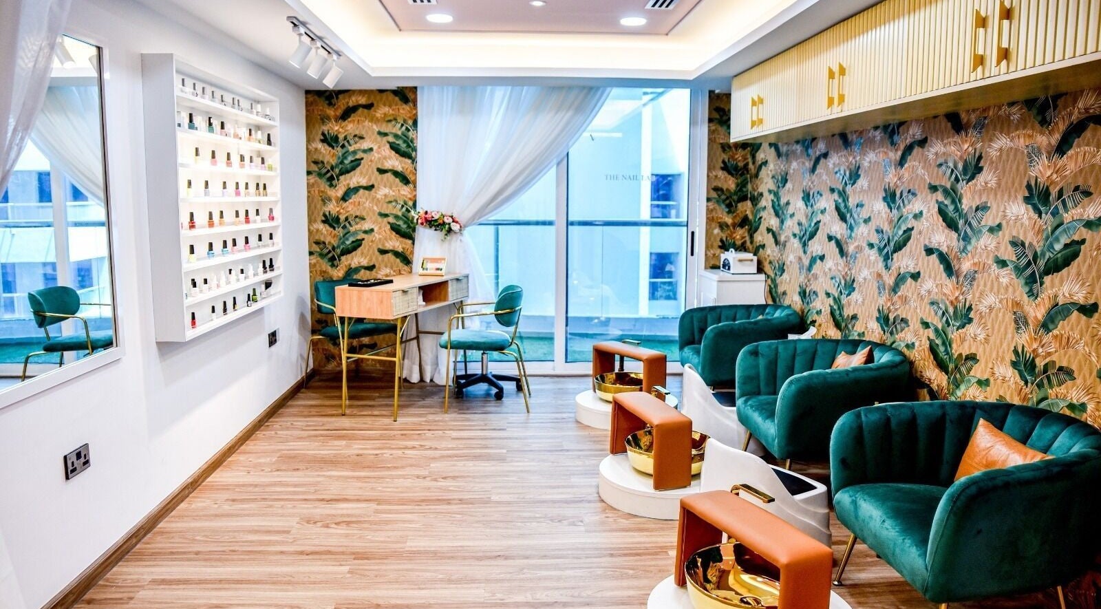 Chic interior at The Beauty Lab Ladies Salon in Abu Dhabi, AE with green chairs and tropical wallpaper.