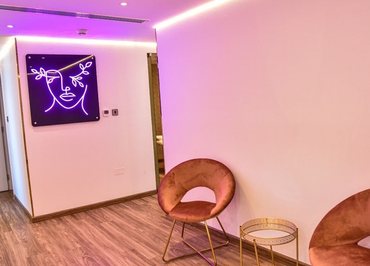 Elegant waiting area at The Beauty Lab Ladies Salon, Abu Dhabi, AE with purple neon art and plush seating.