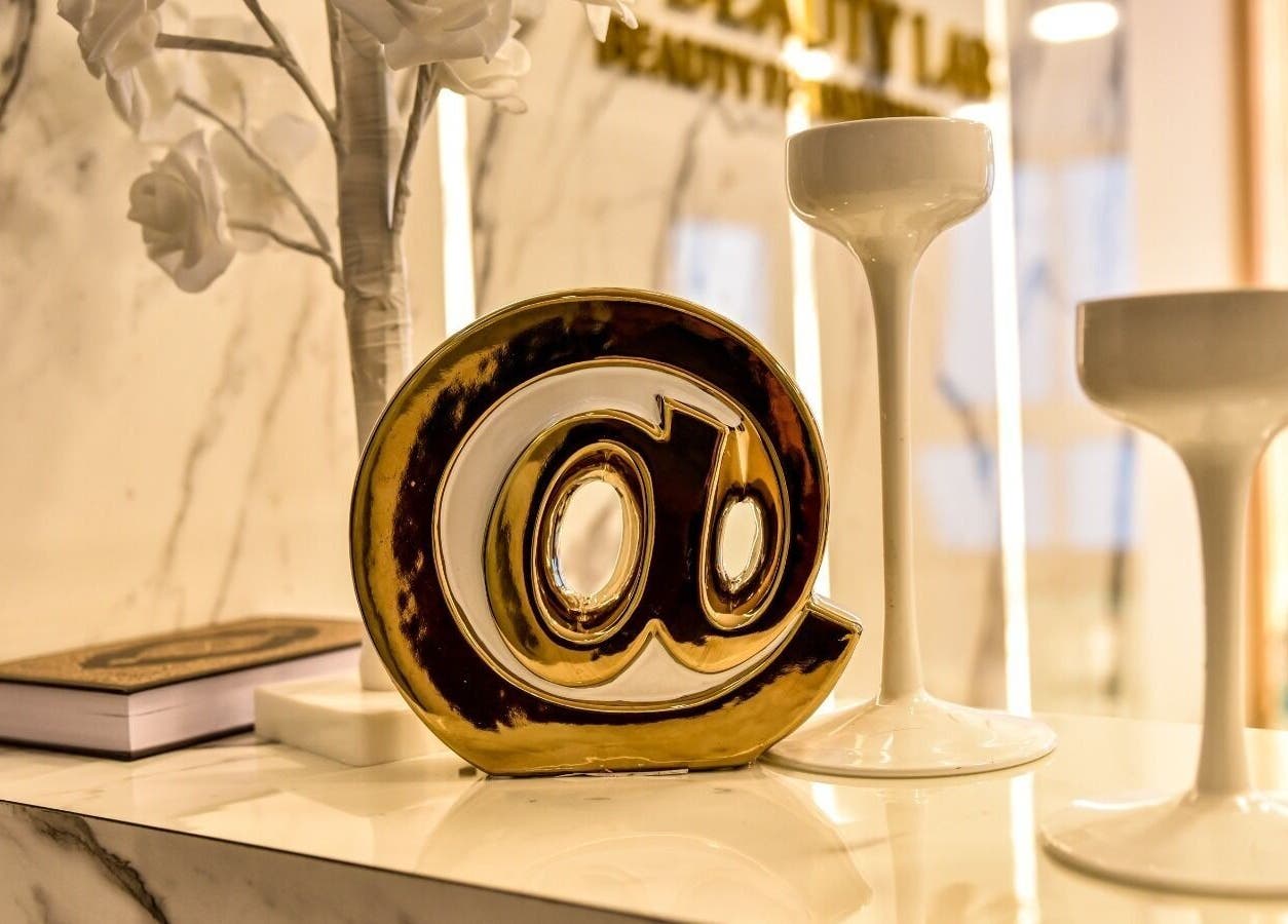 Elegant decor at The Beauty Lab Ladies Salon, Abu Dhabi, AE with golden @ symbol and white vases.