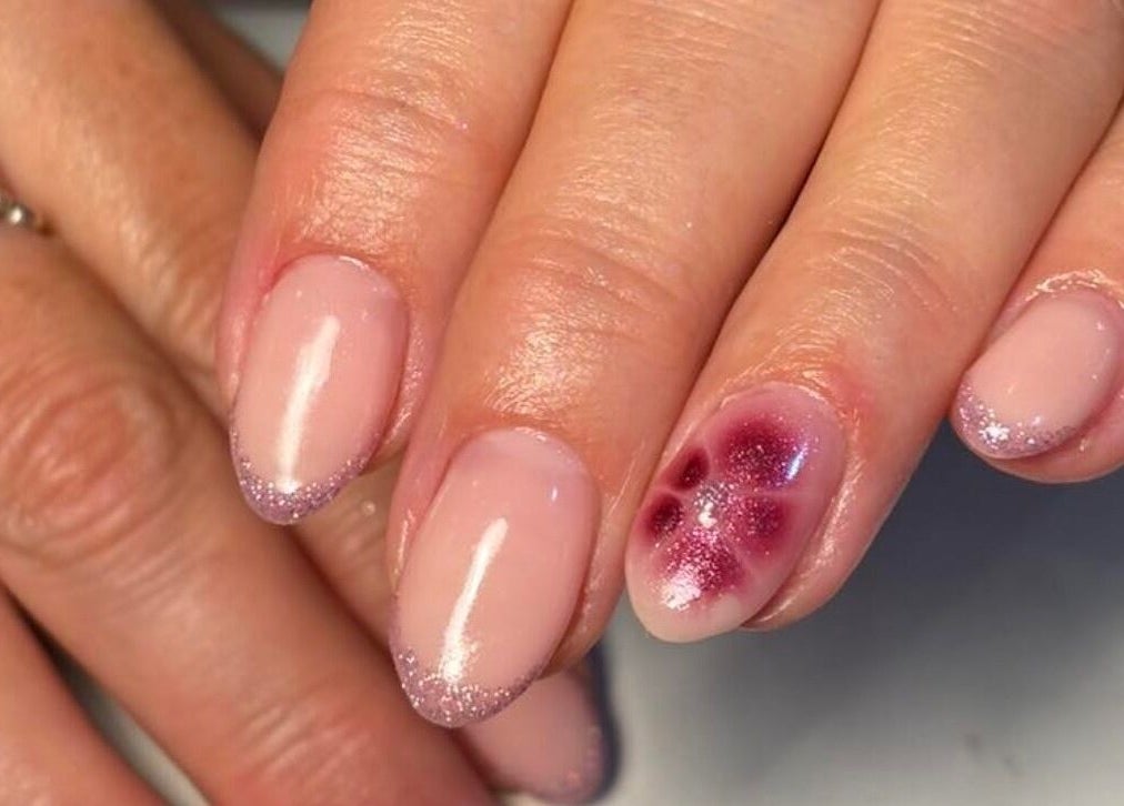 Elegant glitter-tipped manicure with a floral accent at KMbeauty, Ebbw Vale, Wales, GB.