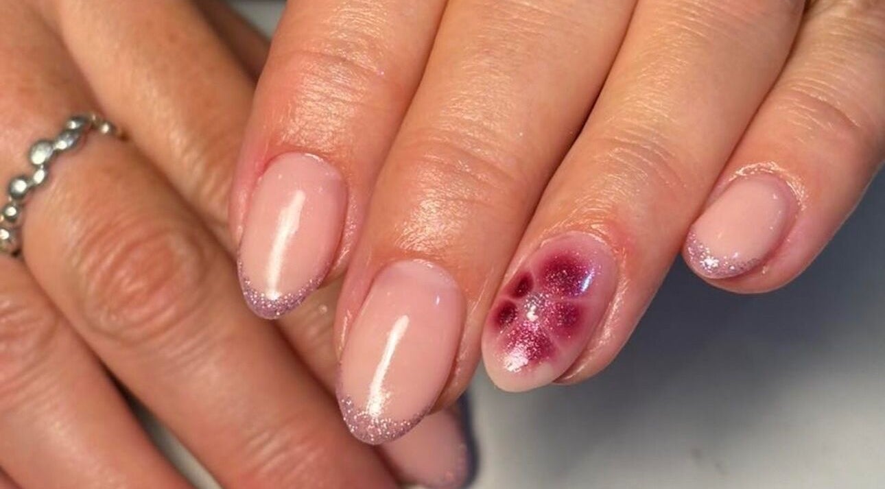 Elegant glitter-tipped manicure with a floral accent at KMbeauty, Ebbw Vale, Wales, GB.