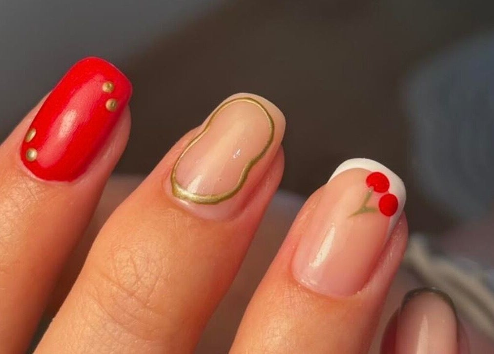 Vibrant nail art with cherry design at KMbeauty, Ebbw Vale, Wales, GB, showcasing glossy red and elegant patterns.