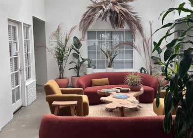 Cozy seating at SB Artistry, Costa Mesa, California, US. Lush plants and natural wood create a serene ambiance.