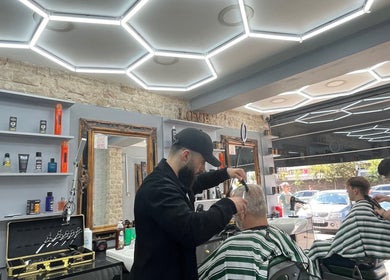 Stylists at work in Hm Barbers, London, England, GB, creating precise cuts under sleek modern lighting.