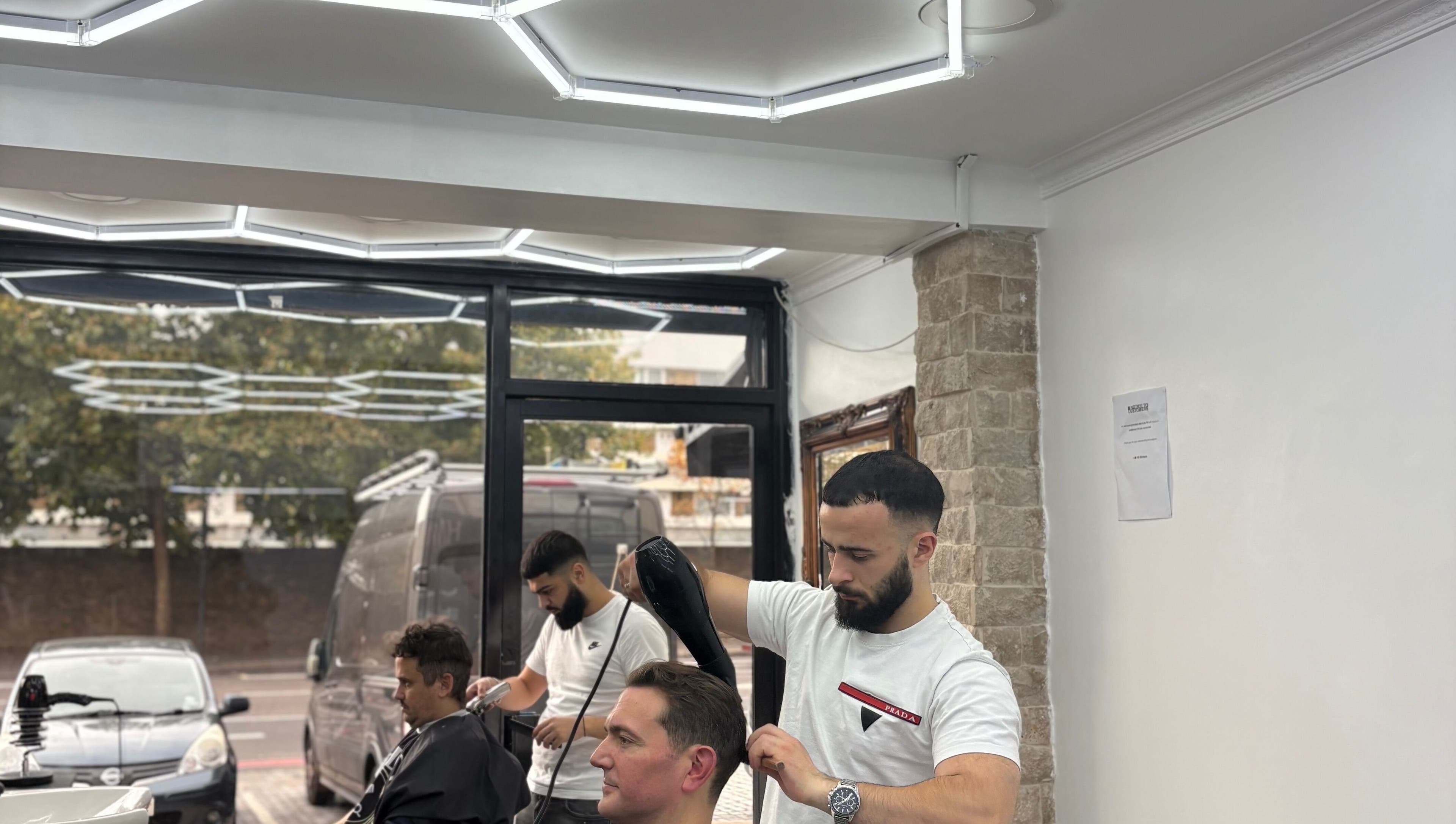 Barber styling hair at Hm Barbers, London, England, GB, with modern interior and attentive service.