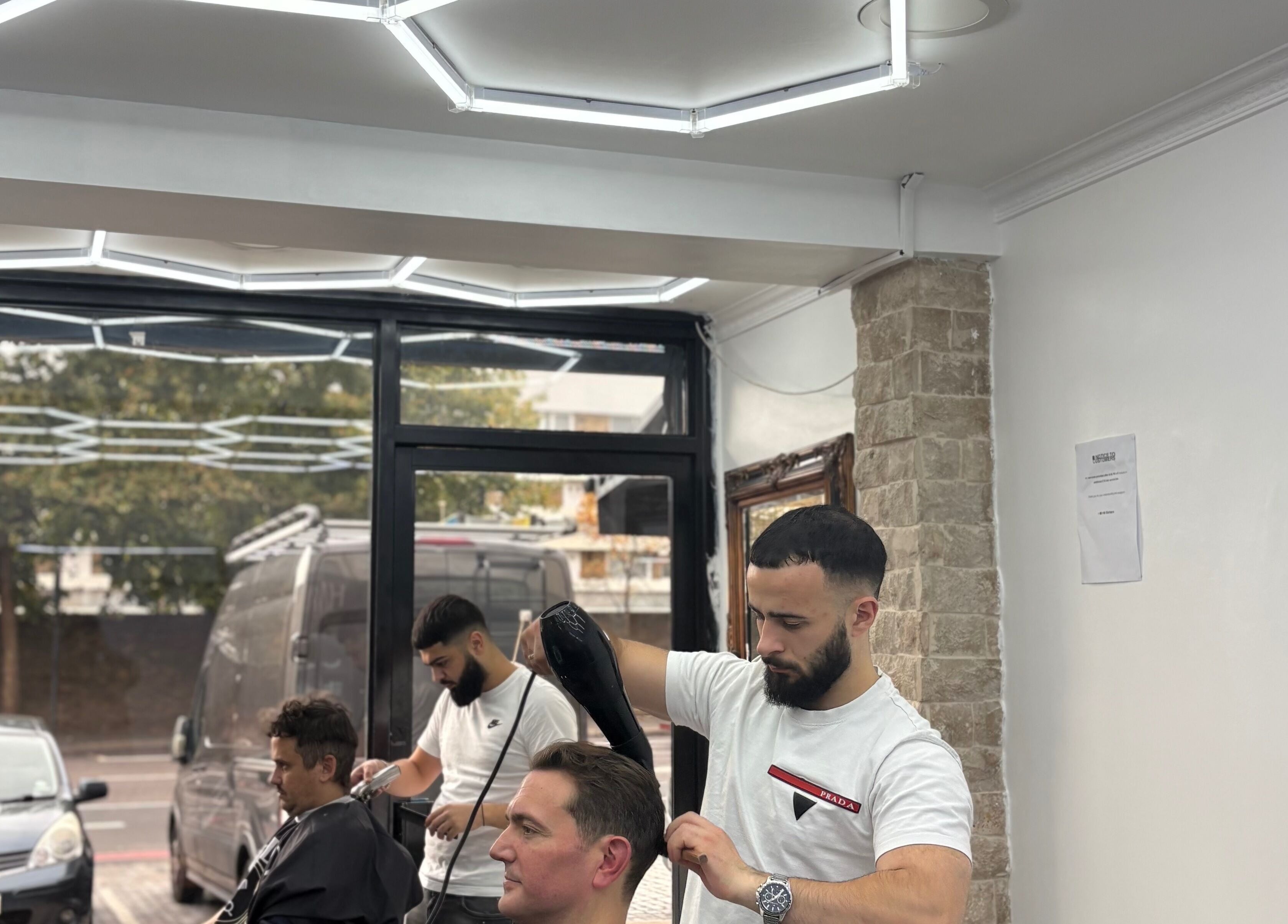 Barber styling hair at Hm Barbers, London, England, GB, with modern interior and attentive service.