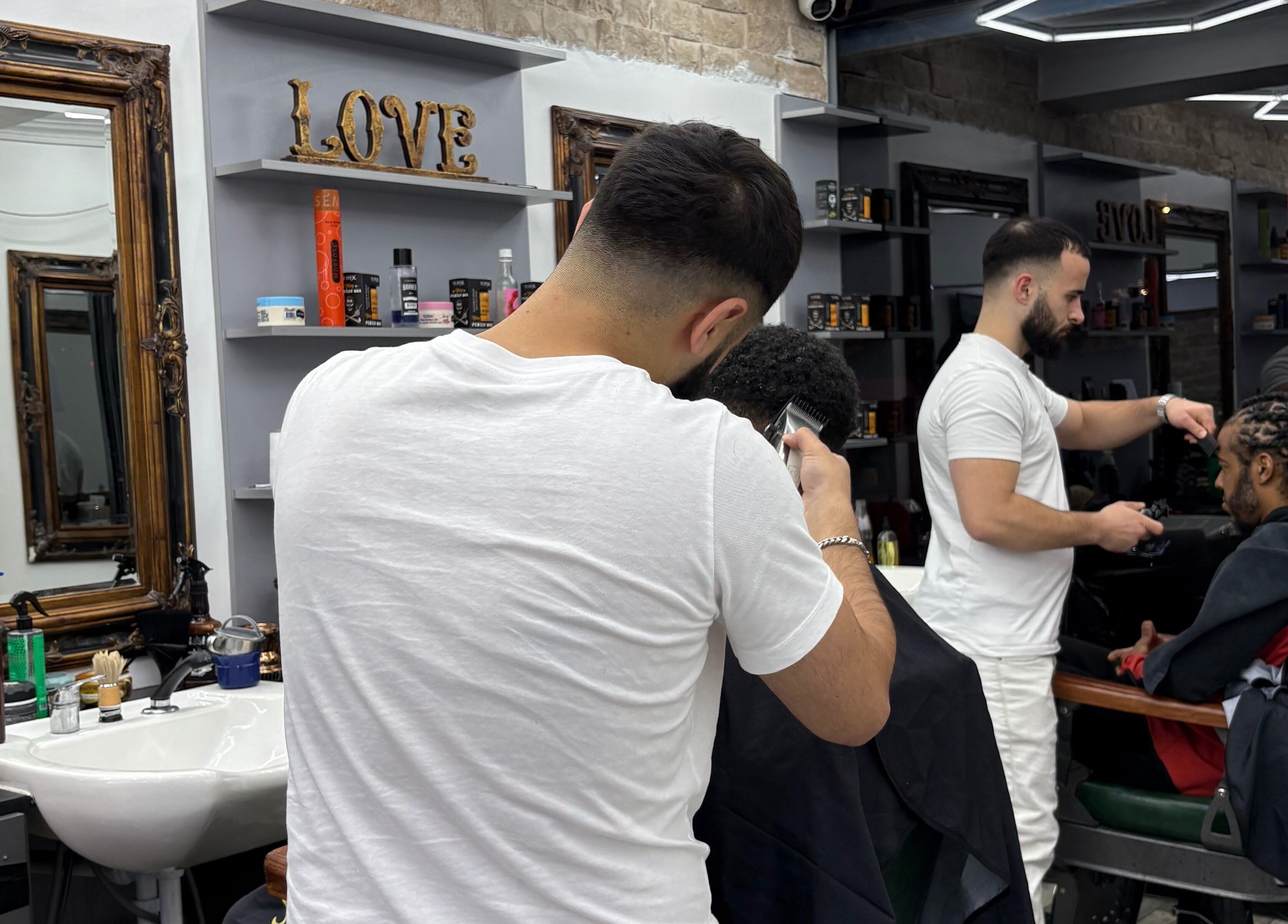 Stylish interior of Hm Barbers in London, England, GB with barbers working on clients.