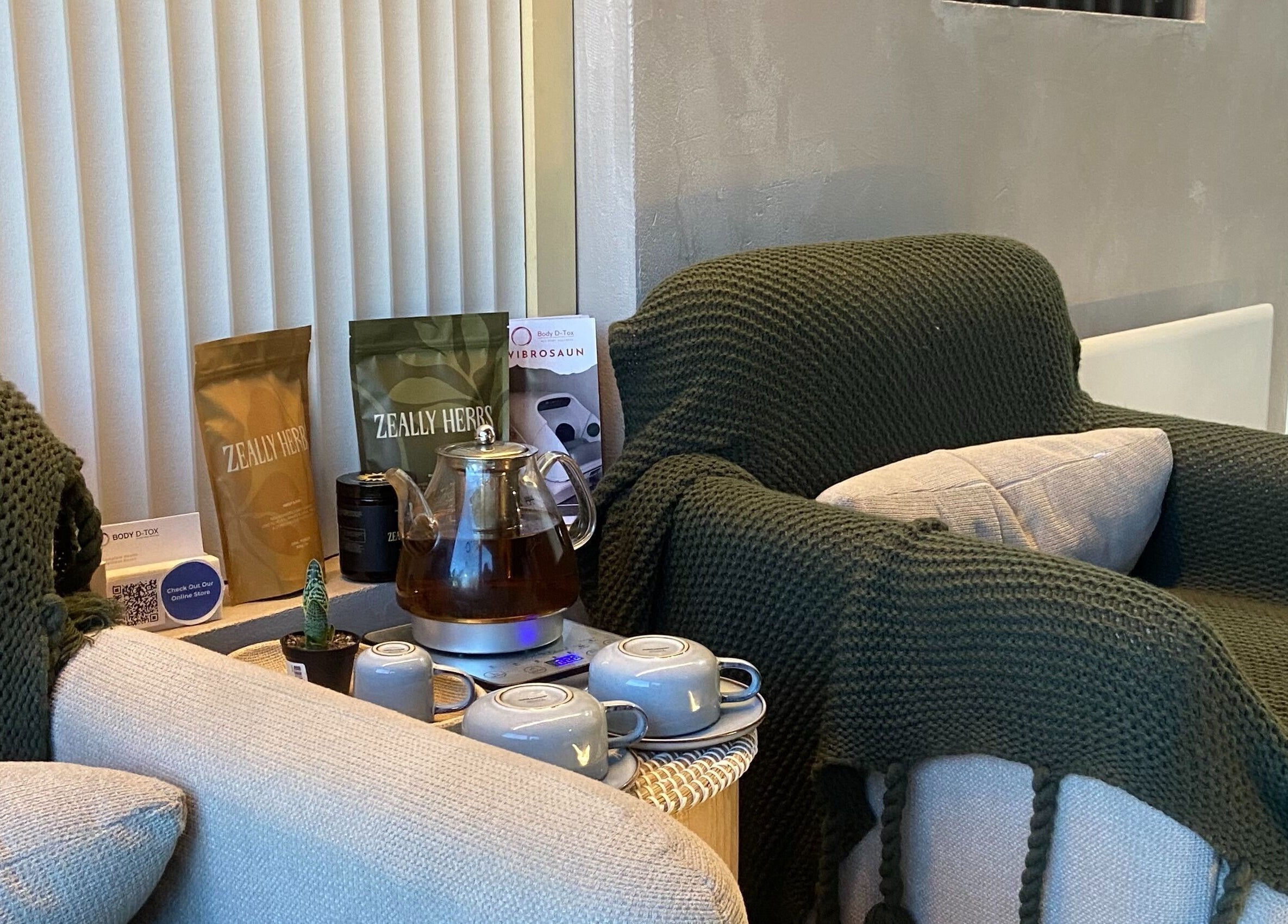 Cozy tea corner at Body D Tox, Melbourne, with knitted green throw, tea set, and herbal products.