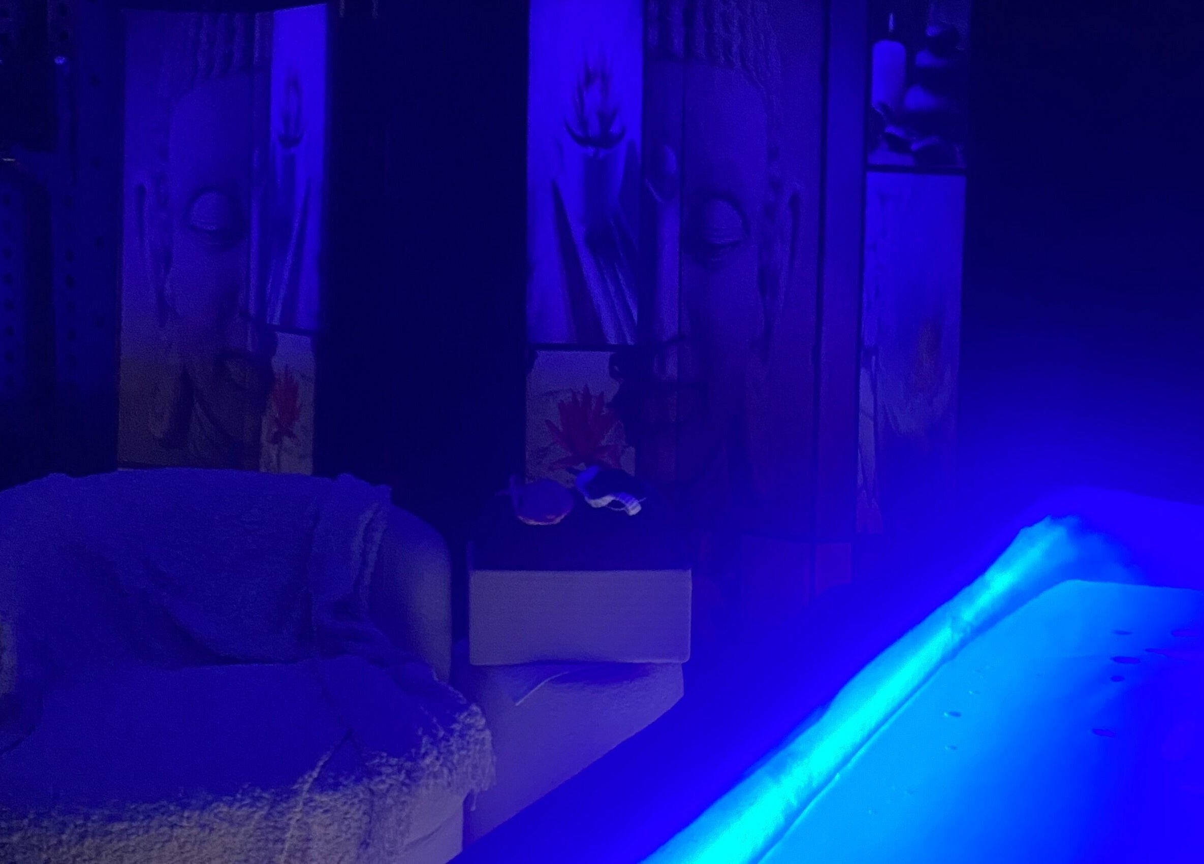 Relaxing spa ambiance with blue lighting at Body D Tox, Melbourne, Victoria, AU, featuring a cozy chair and Buddha art.