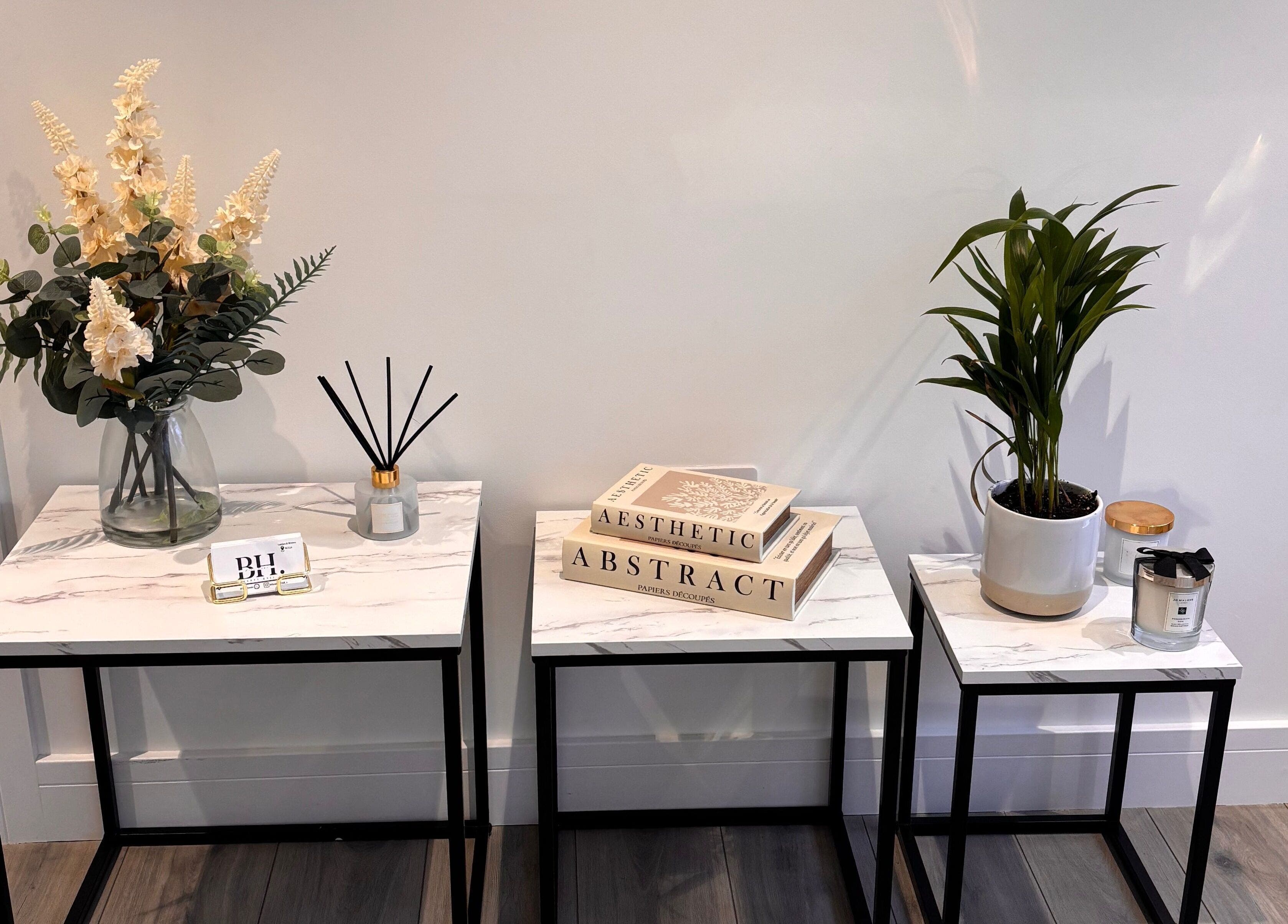 Elegant decor at Beauty Hall, Watford, England featuring marble tables and lush plants.