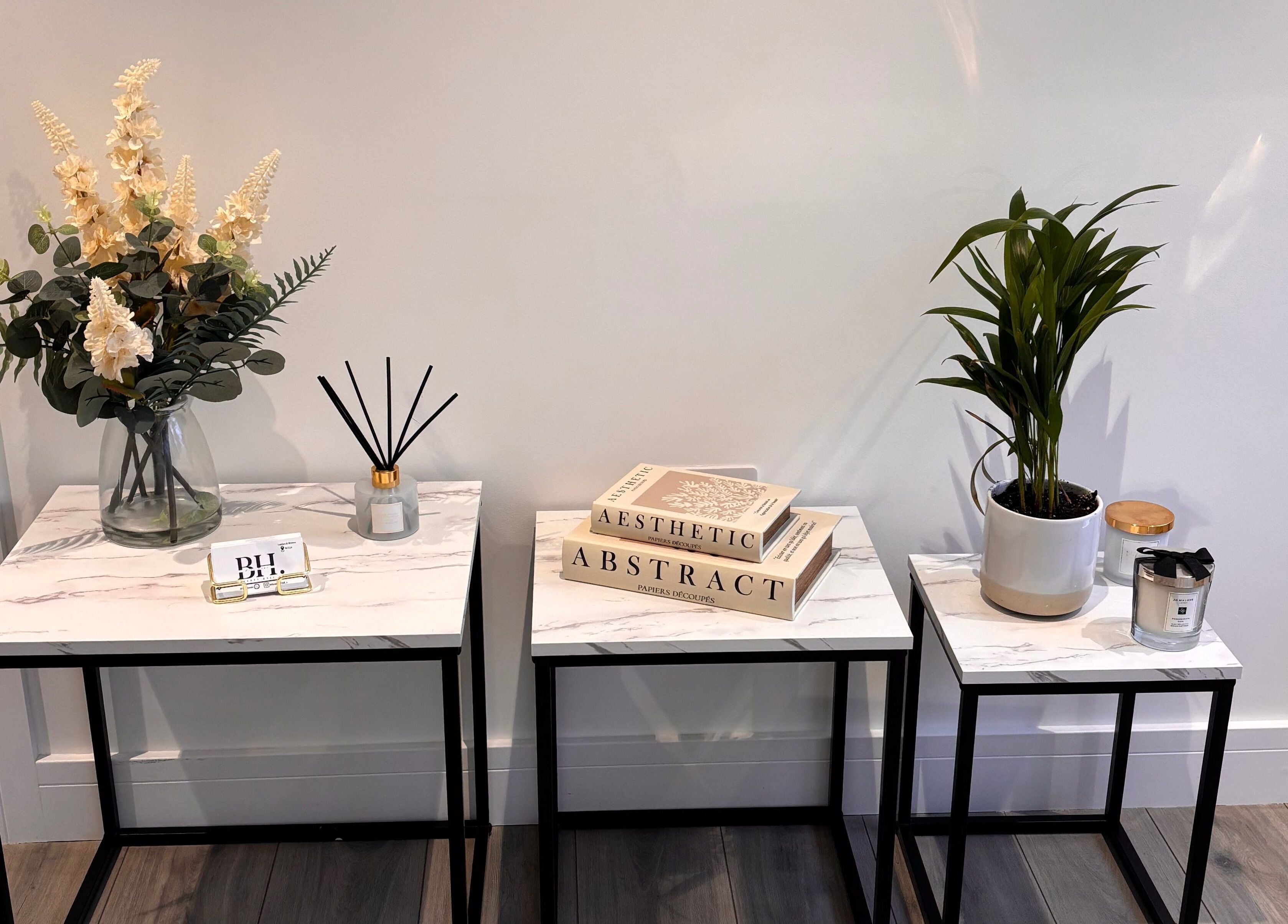 Elegant decor at Beauty Hall, Watford, England featuring marble tables and lush plants.