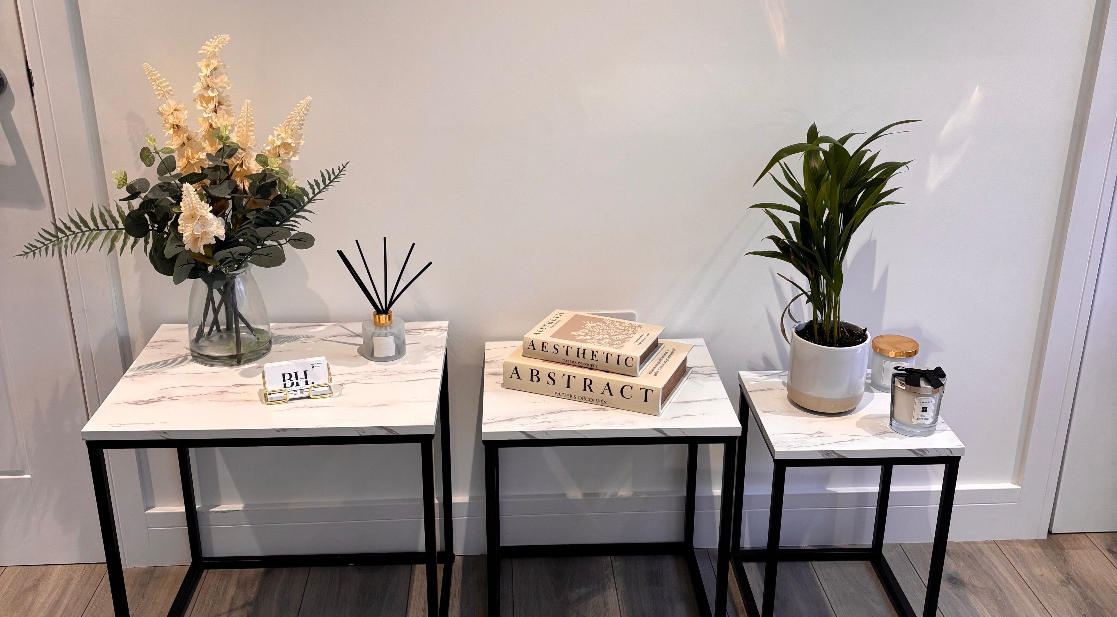 Elegant decor at Beauty Hall, Watford, England featuring marble tables and lush plants.
