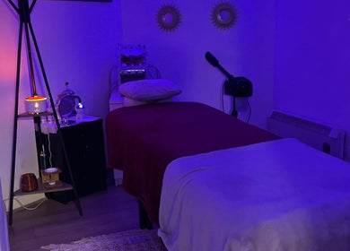 Serene massage room at Unique Beauty House, Reading, England, GB with calming purple lighting and cozy setup.