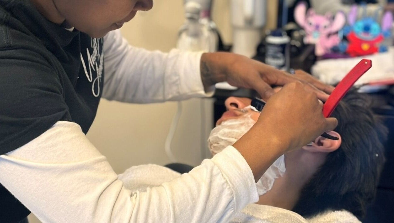 Expert barber shaving a client at Uncut Barber Academy in Savannah, Georgia, US.