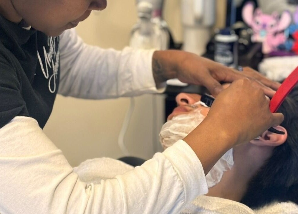 Expert barber shaving a client at Uncut Barber Academy in Savannah, Georgia, US.