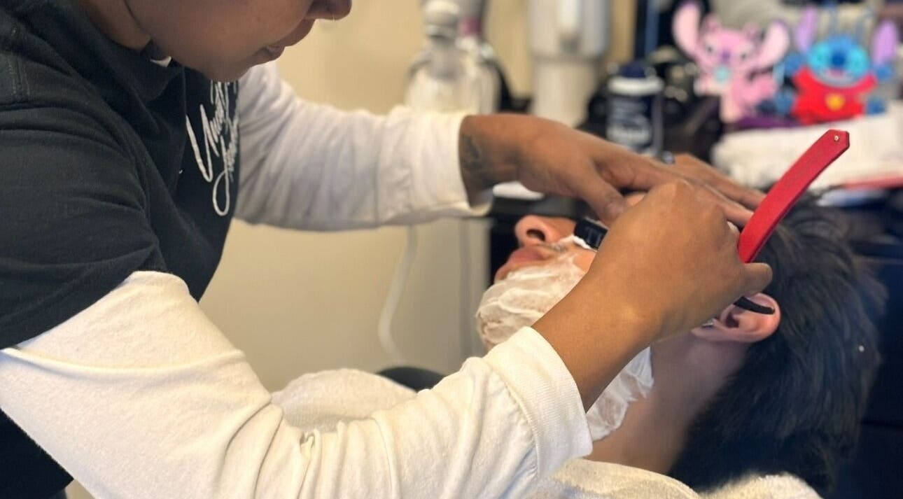Expert barber shaving a client at Uncut Barber Academy in Savannah, Georgia, US.