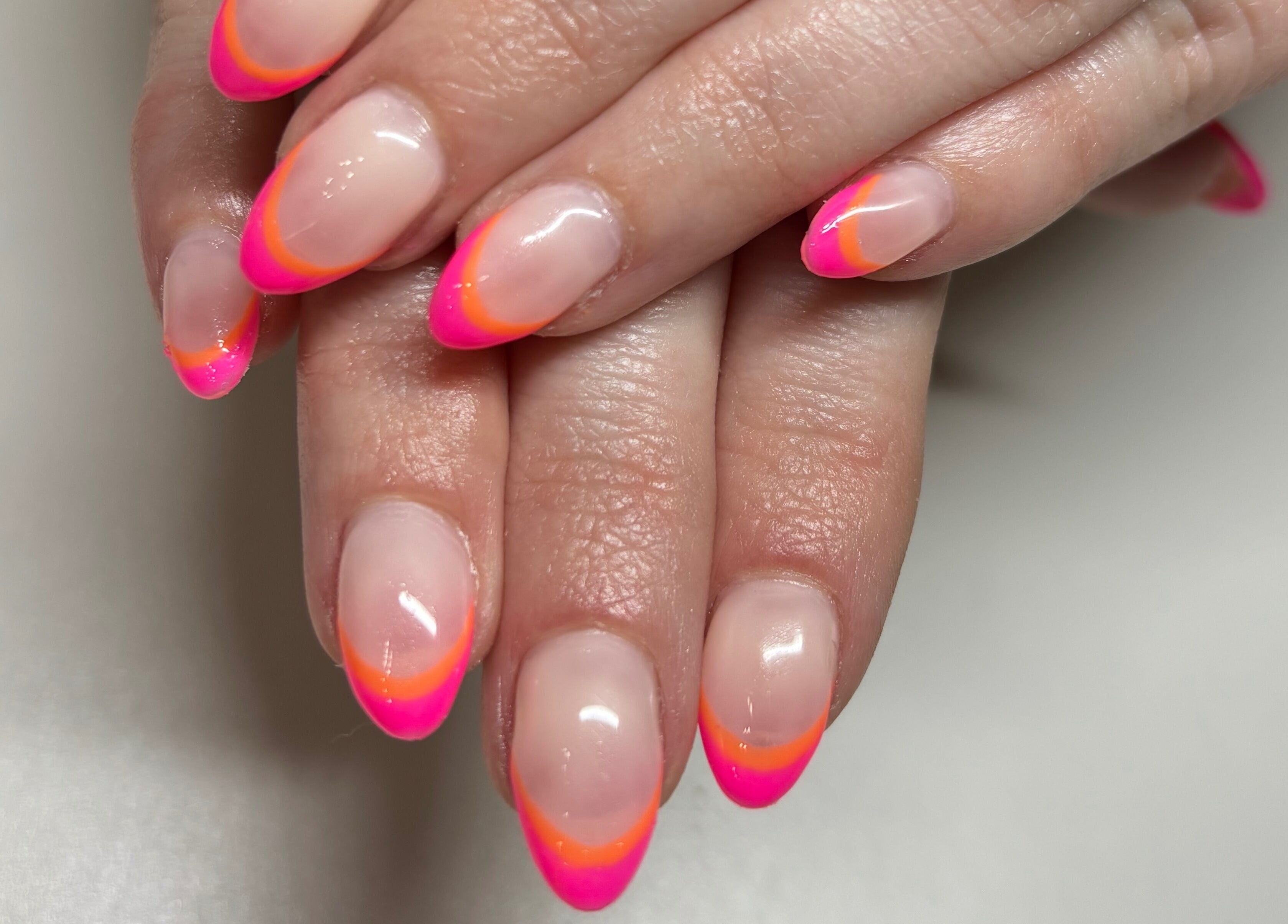 Neon pink and orange manicure at Gwen's Aesthetics, Pembroke, Ontario, CA, showcasing stylish nail art.