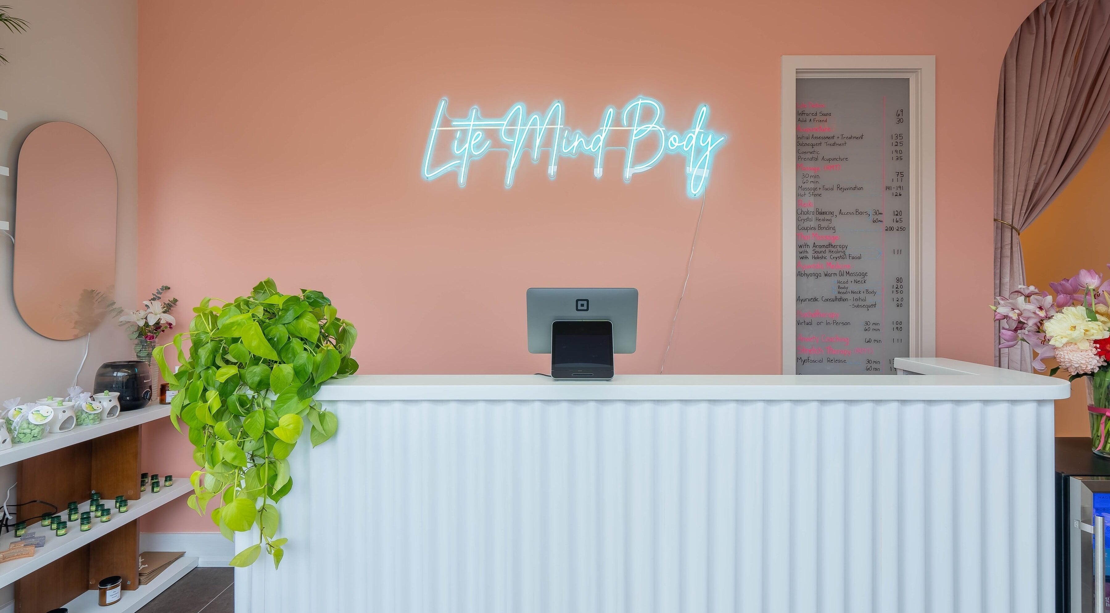 Reception at Lite Mind Body Clinic - Harbord Village in Toronto, Ontario, CA with neon sign and plants.