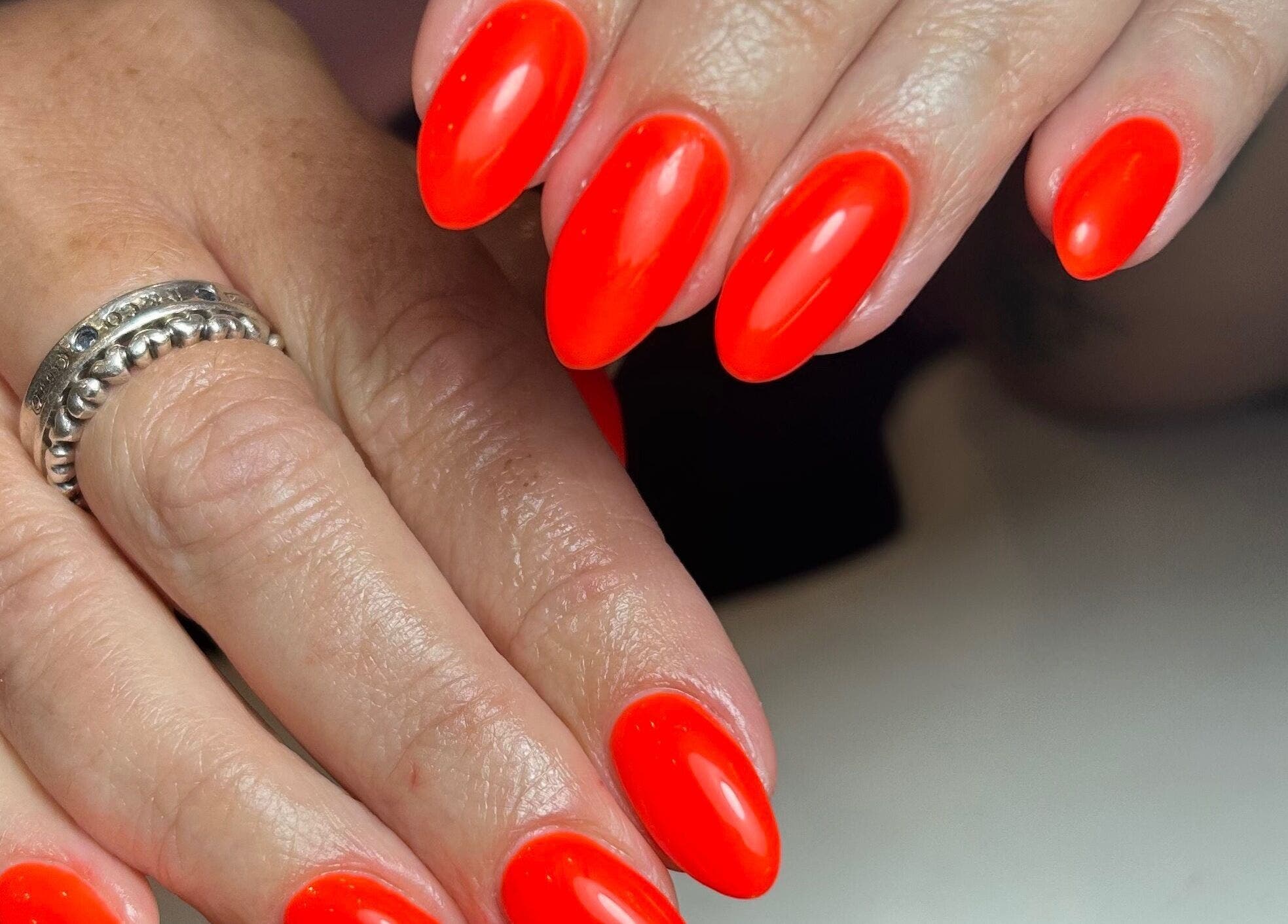 Flawlessly manicured nails with bright red polish at Pure Nails by Rachel, Newtown, Wales, GB.