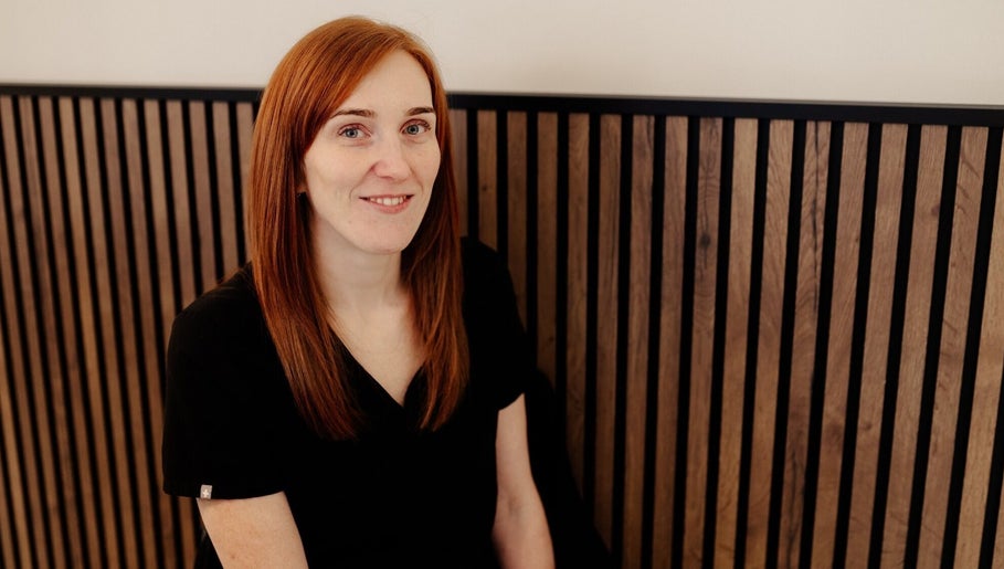 Friendly staff member at Eivissa Wellbeing, Lancaster, England, GB, in warm wooden setting.