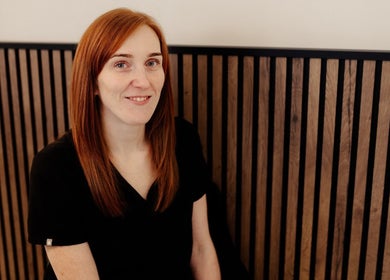 Friendly staff member at Eivissa Wellbeing, Lancaster, England, GB, in warm wooden setting.