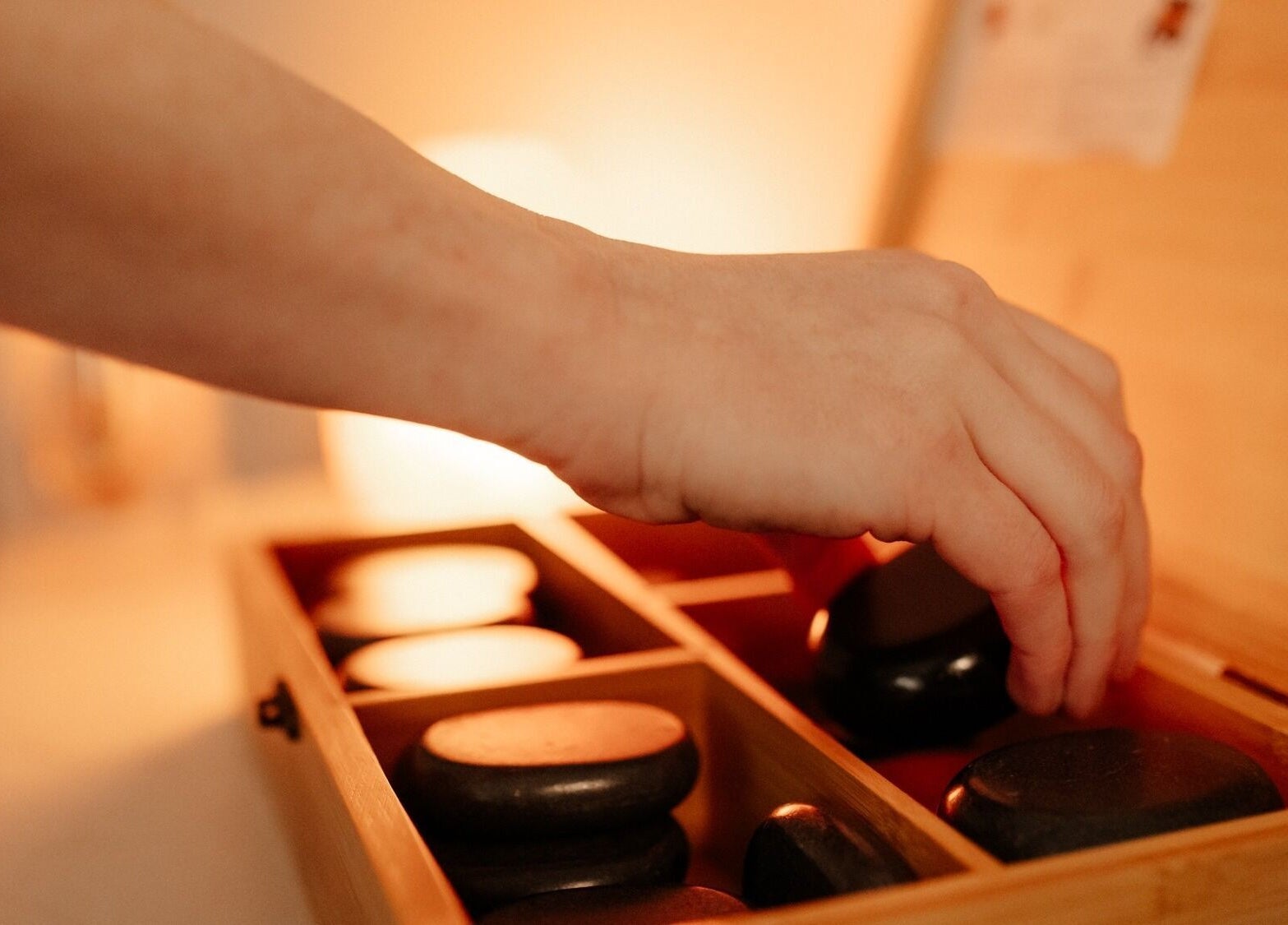 Hand selecting a stone from a wooden box at Eivissa Wellbeing, Lancaster, England, GB.