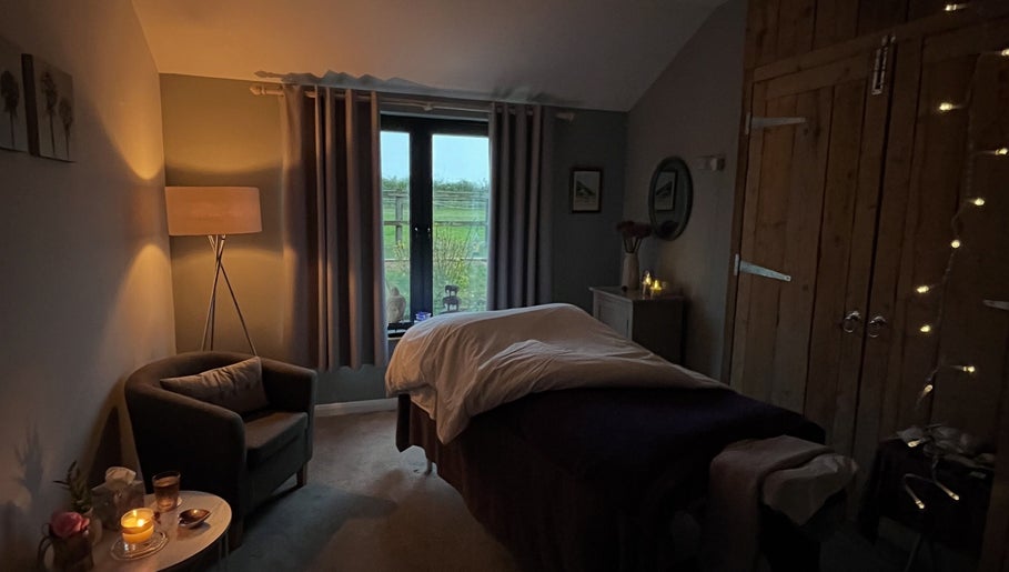 Serene massage room at The Tranquility Skin Barn, Swainsthorpe, England, GB, featuring ambient lighting and soft decor.