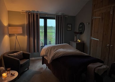 Serene massage room at The Tranquility Skin Barn, Swainsthorpe, England, GB, featuring ambient lighting and soft decor.