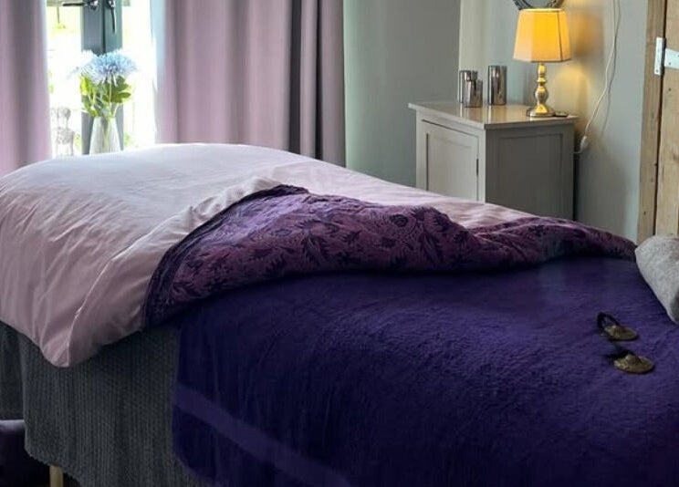 Relaxing massage room at The Tranquility Skin Barn, Swainsthorpe, England, GB, featuring soft purple tones.