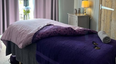 Relaxing massage room at The Tranquility Skin Barn, Swainsthorpe, England, GB, featuring soft purple tones.