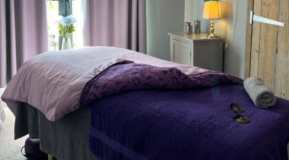Relaxing massage room at The Tranquility Skin Barn, Swainsthorpe, England, GB, featuring soft purple tones.