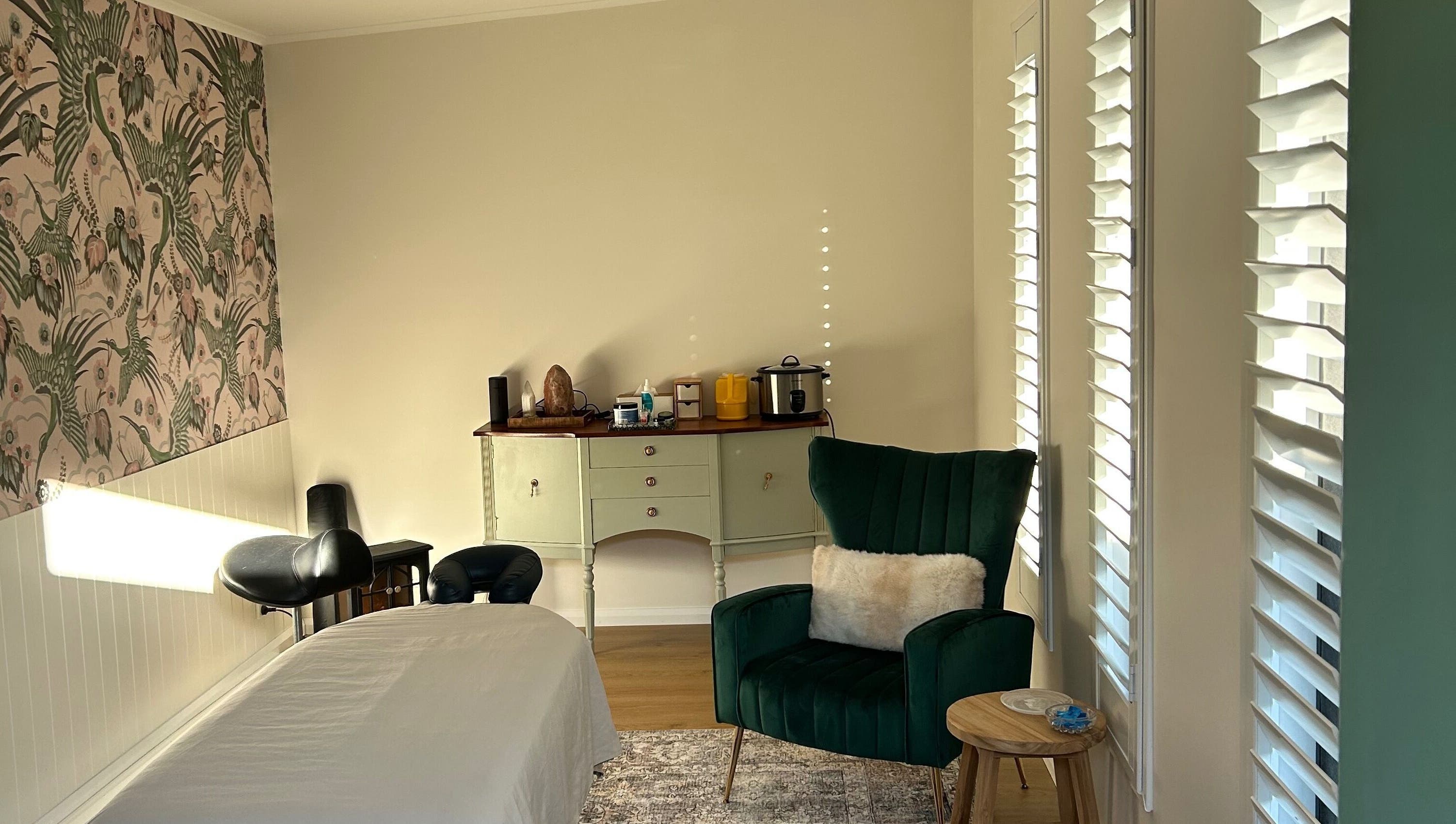 Relaxing space at Absolute Health and Harmony, Berkeley Vale, New South Wales, AU, with a massage bed and cozy chair.