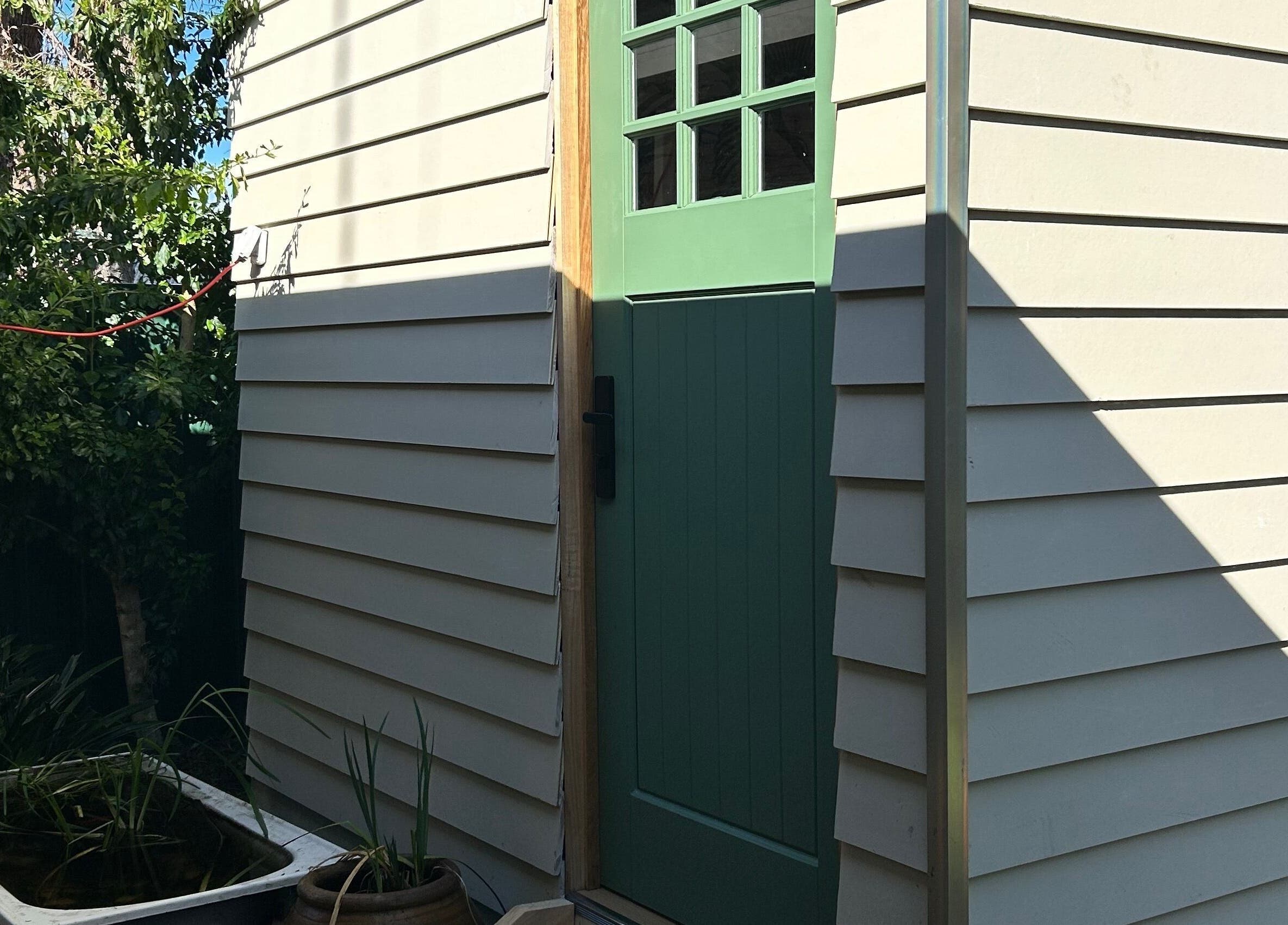 Charming green door at Absolute Health and Harmony, Berkeley Vale, New South Wales, AU surrounded by greenery.