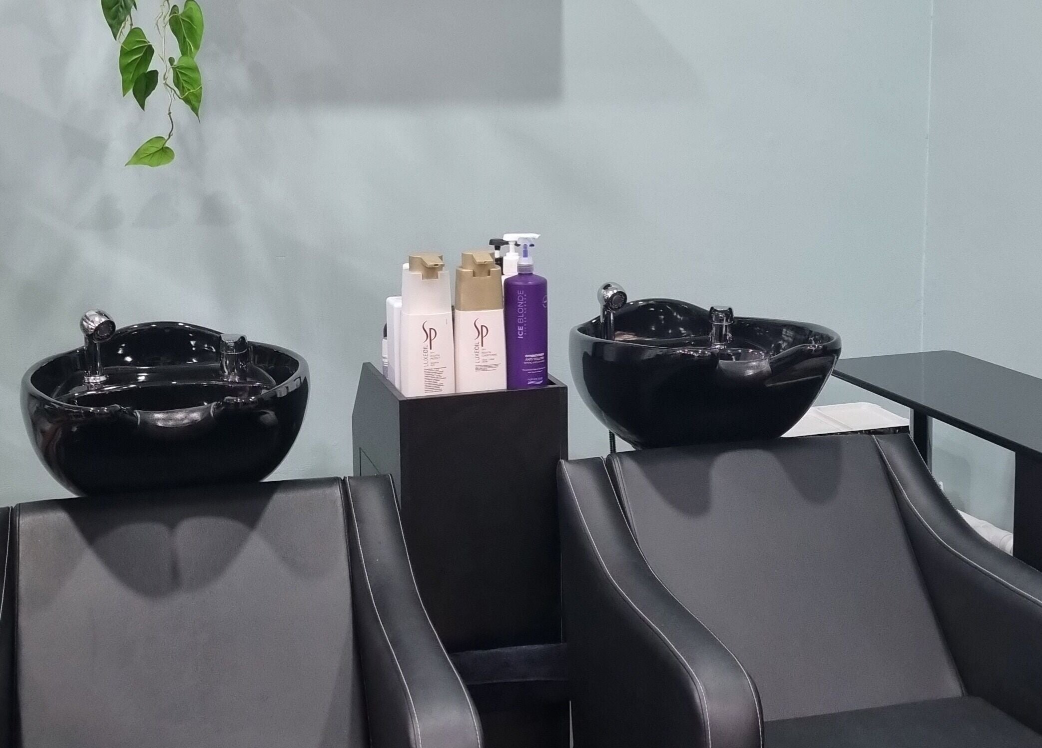 Elegant wash stations at Hair Majesty, Riverton, Western Australia, AU, featuring sleek black basins and chairs.