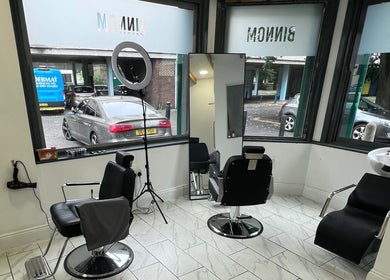 Modern salon interior at Binnom Hair, Newcastle upon Tyne, England, GB with styling chairs and large windows.