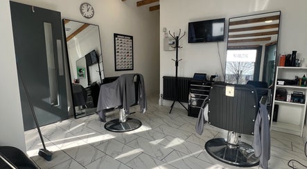 Modern salon interior at Binnom Hair, Newcastle upon Tyne, England, GB, featuring sleek chairs and large mirrors.